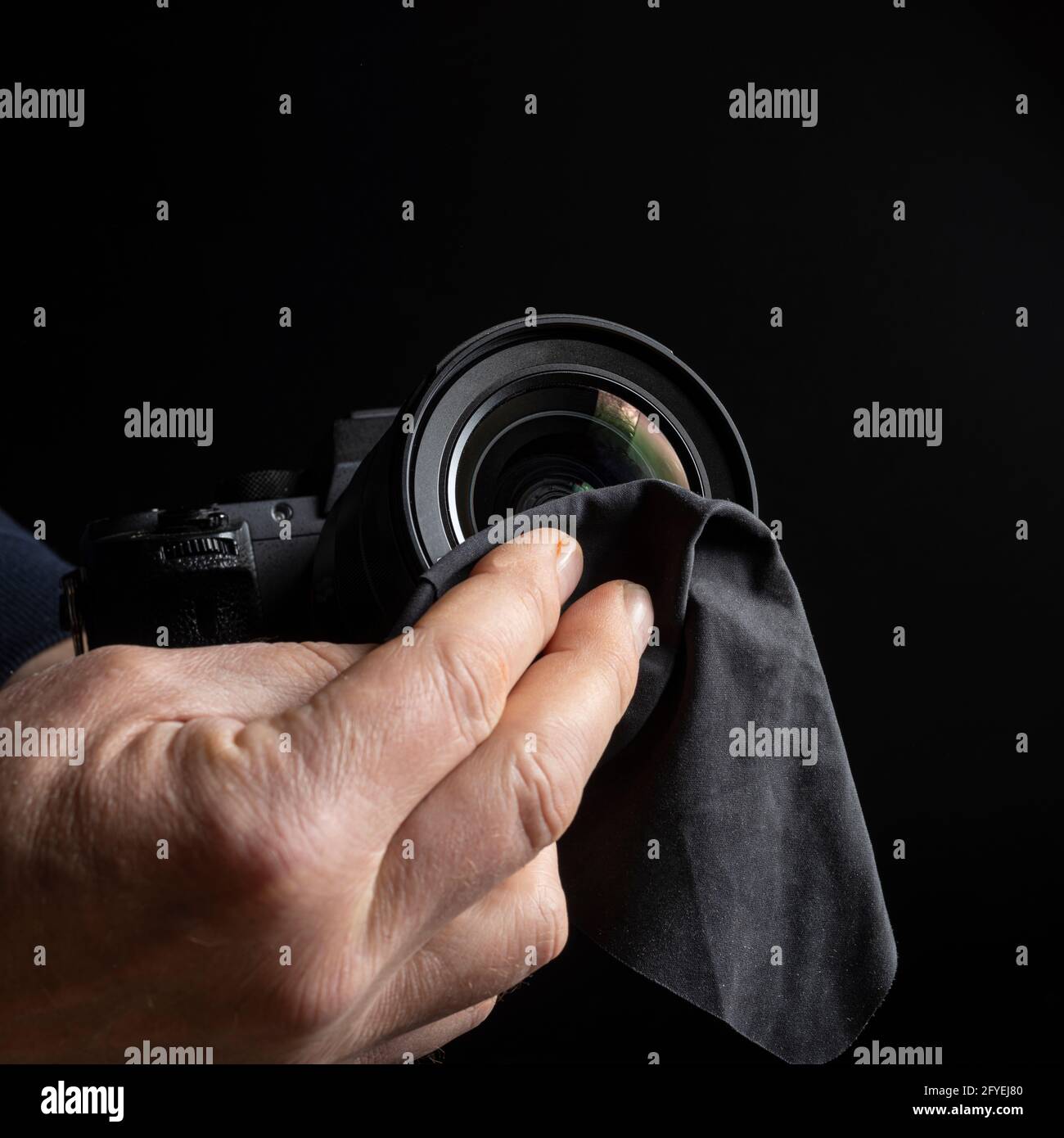a man cleaning the front lens of a camera lens Stock Photo