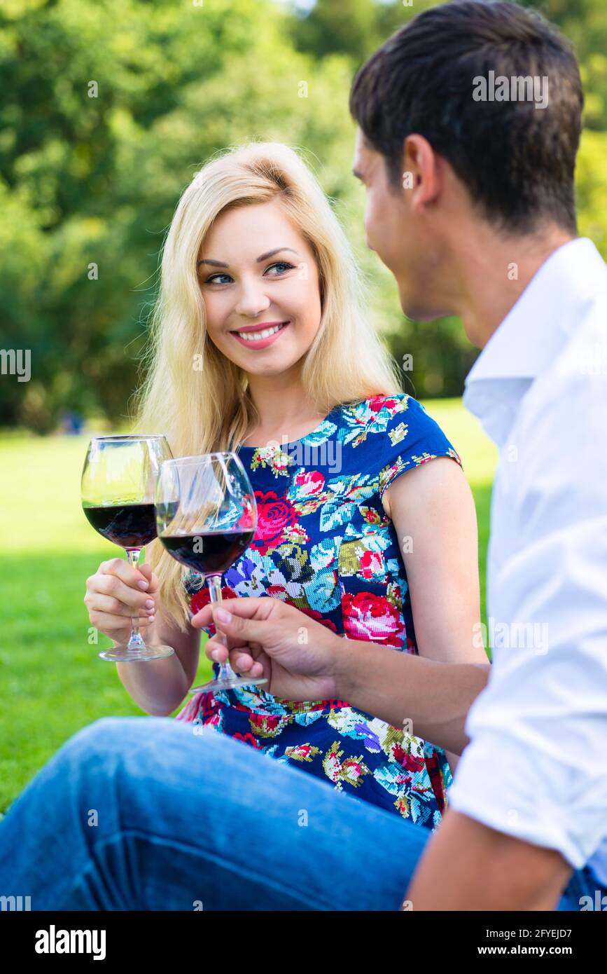 Couple drinking red wine on grass of park at picnic Stock Photo - Alamy