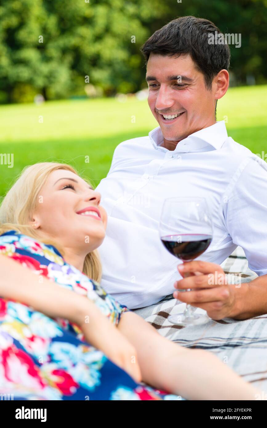 Couple drinking red wine on grass of park at picnic Stock Photo - Alamy