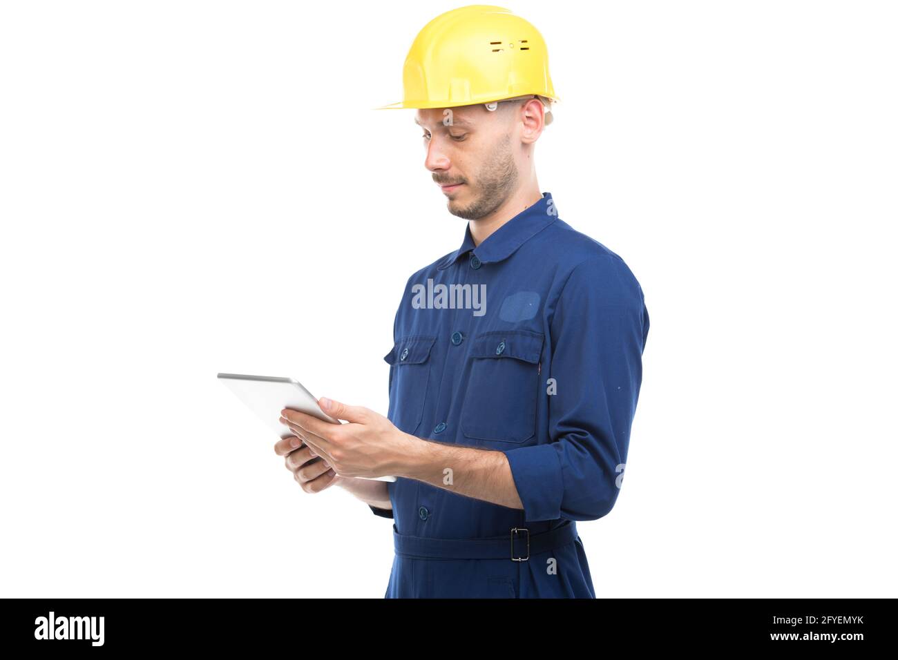 Horizontal medium portrait of successful handsome young adult Caucasian construction engineer wearing uniform using digital tablet, white background Stock Photo