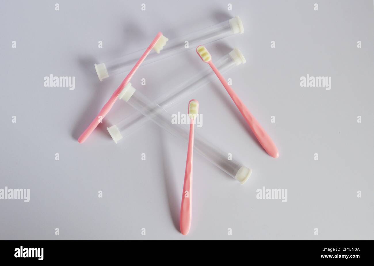 Pink superfine Japanese style plastic toothbrushes and its tubes in gray background Stock Photo