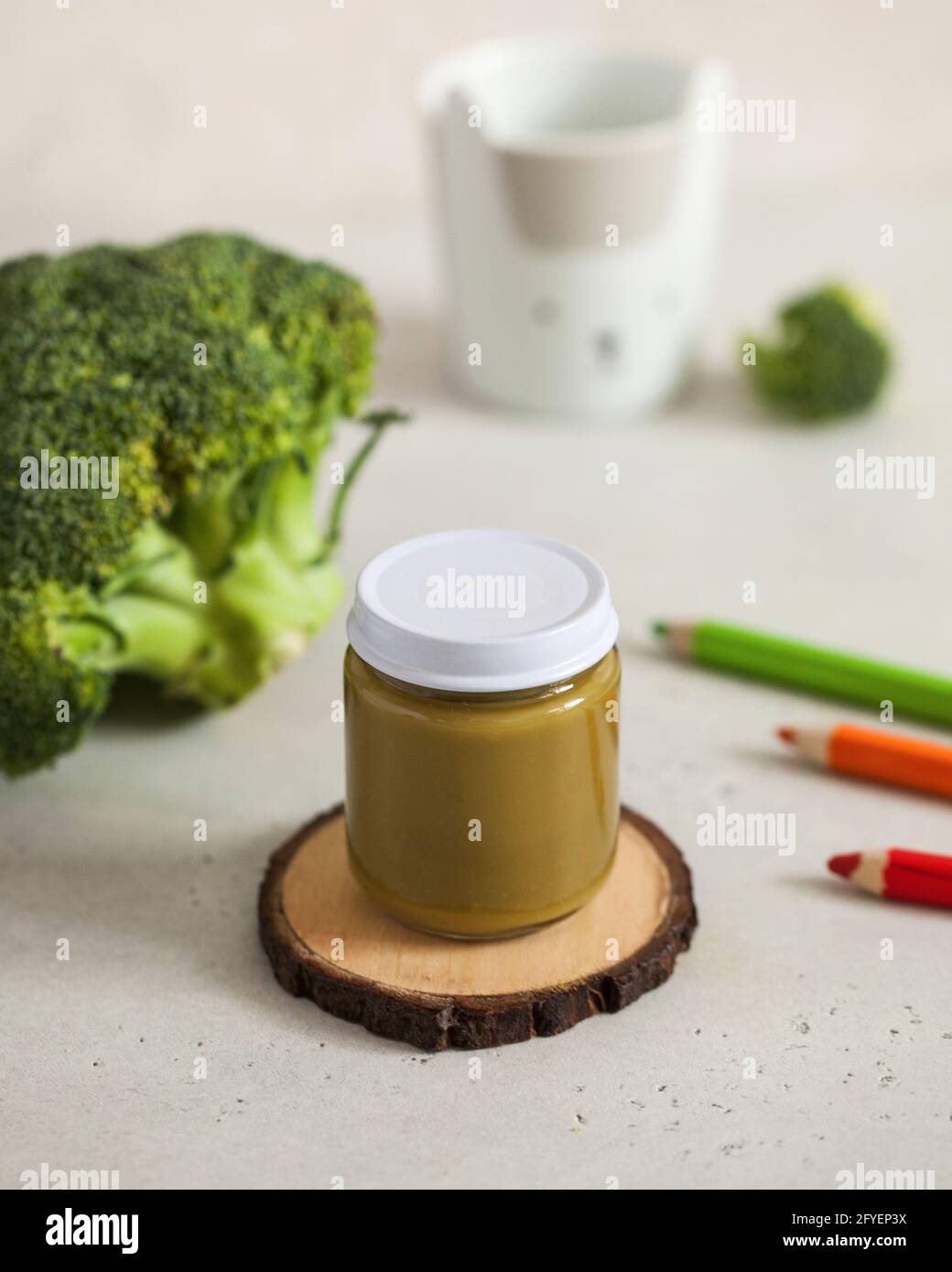 Closed glass jar with baby food broccoli puree with fresh broccoli and colored pencils Layout. The concept of baby food Stock Photo