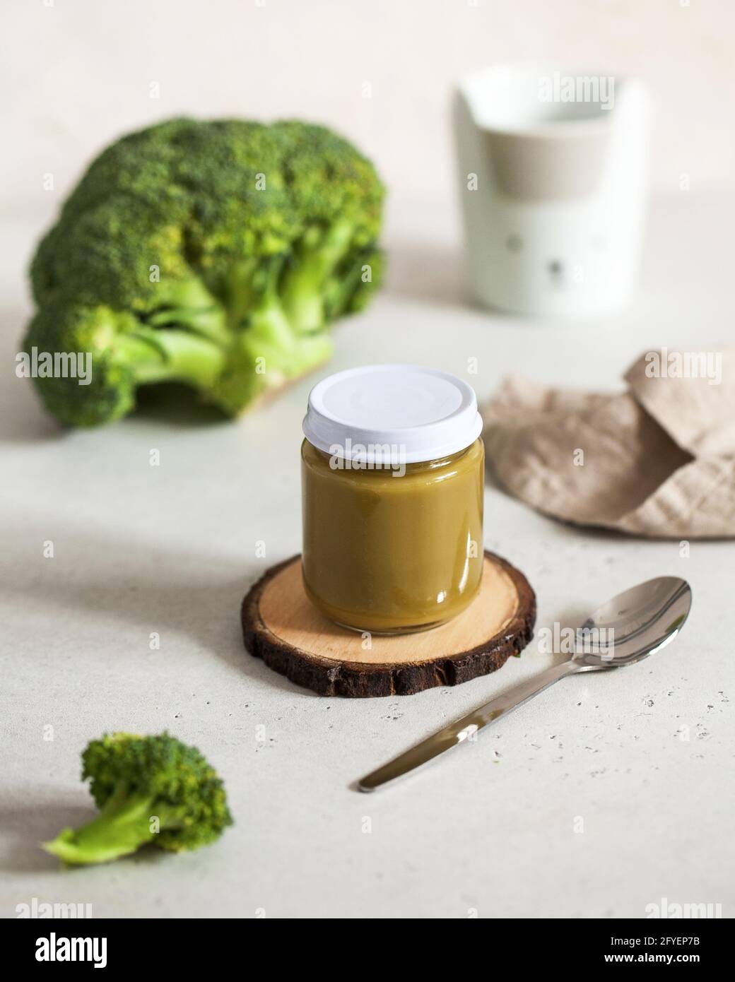 glass jar with baby food broccoli smoothie with a spoon with fresh broccoli. Layout Baby food concept, first feeding. Stock Photo