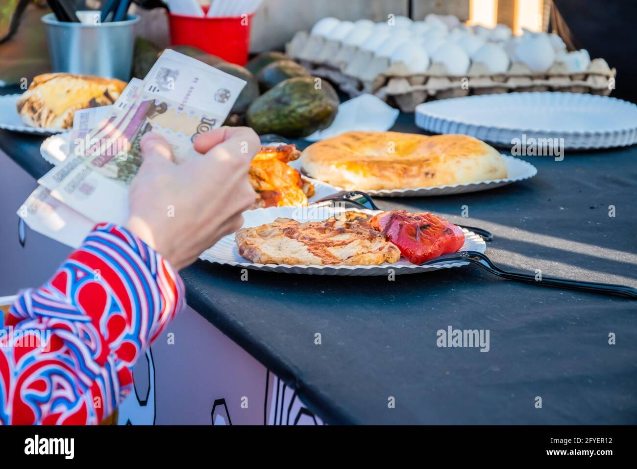 Close-up of a woman's hand with a paper currency, a customer makes an order at the counter of an open-air Mexican food restaurant. Food festival in th Stock Photo
