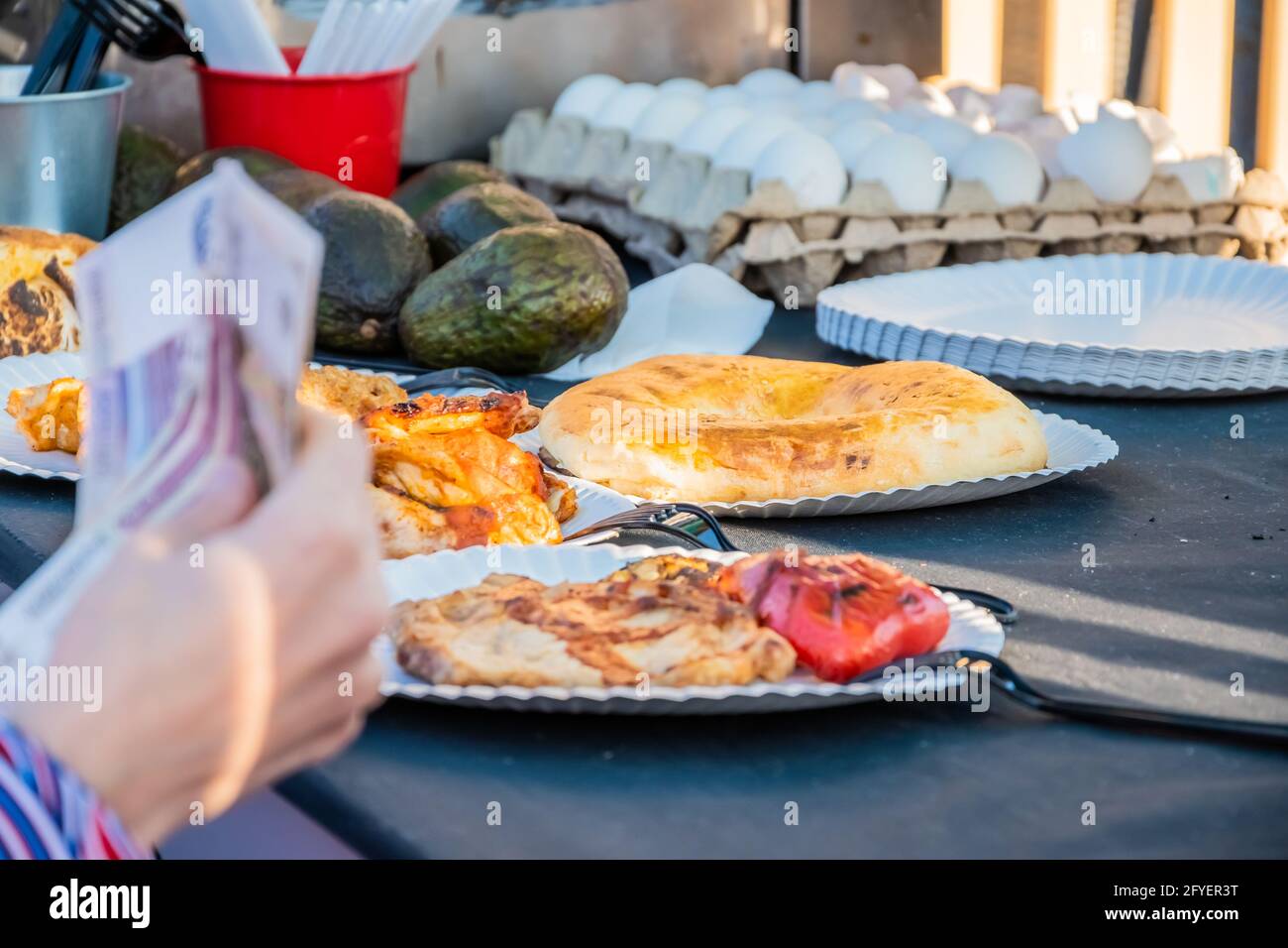 Close-up of a woman's hand with a paper currency, a customer makes an order at the counter of an open-air Mexican food restaurant. Food festival in th Stock Photo