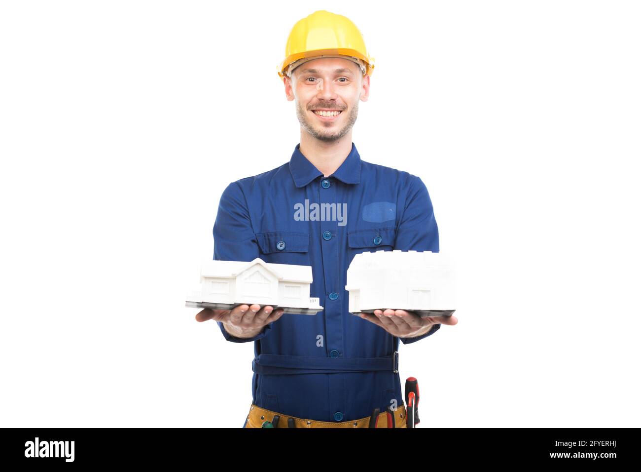 Horizontal medium portrait of modern handsome young adult Caucasian engineer wearing blue uniform holding two house models, white background Stock Photo