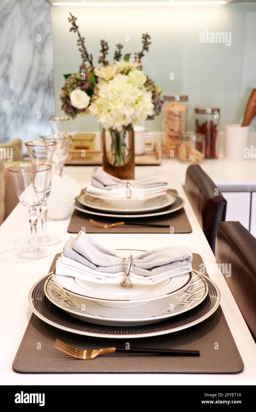 tableware for dinner consis of three size plates with two wine glasses, knife and fork, two napkins put on the counter in kitchen Stock Photo