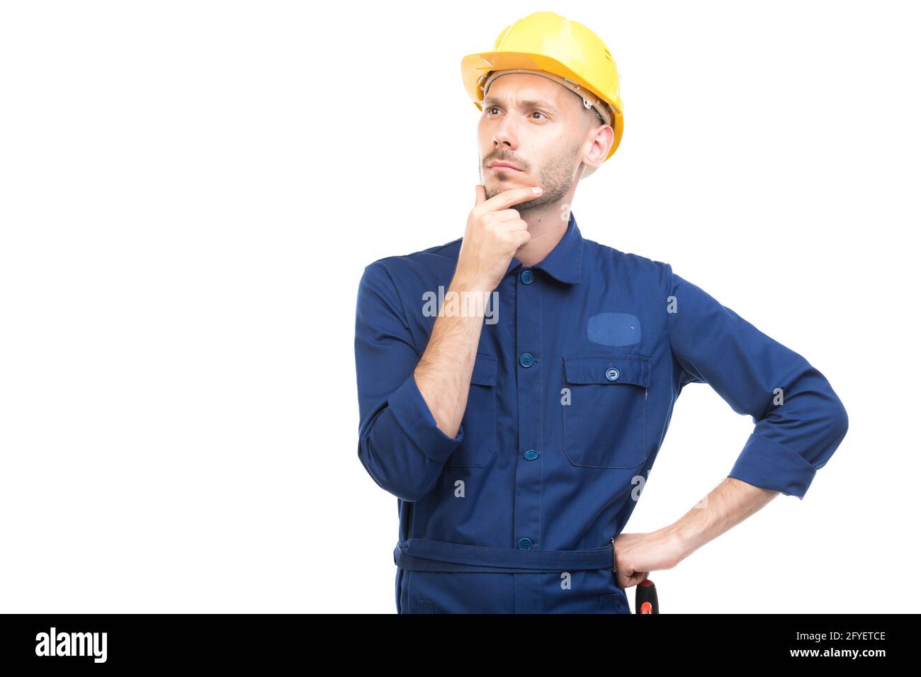Horizontal medium portrait of modern handsome young adult Caucasian engineer wearing blue uniform thinking about something, white background Stock Photo