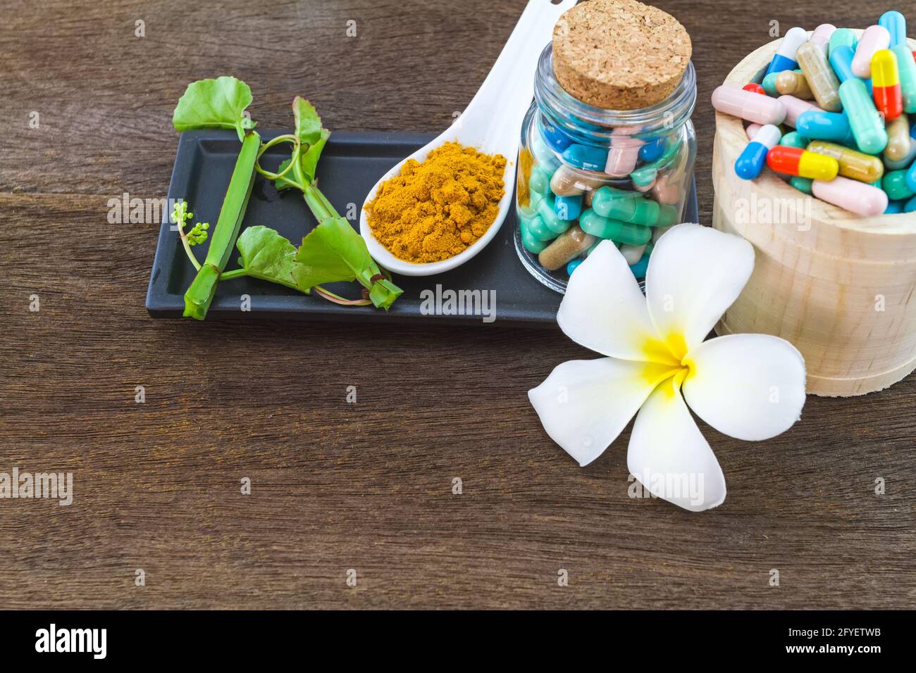 Spa herbal (white frangipani flowers, turmeric powder in white spoon ,pill,Cissus Quadrangularis Linn) on wooden background Stock Photo