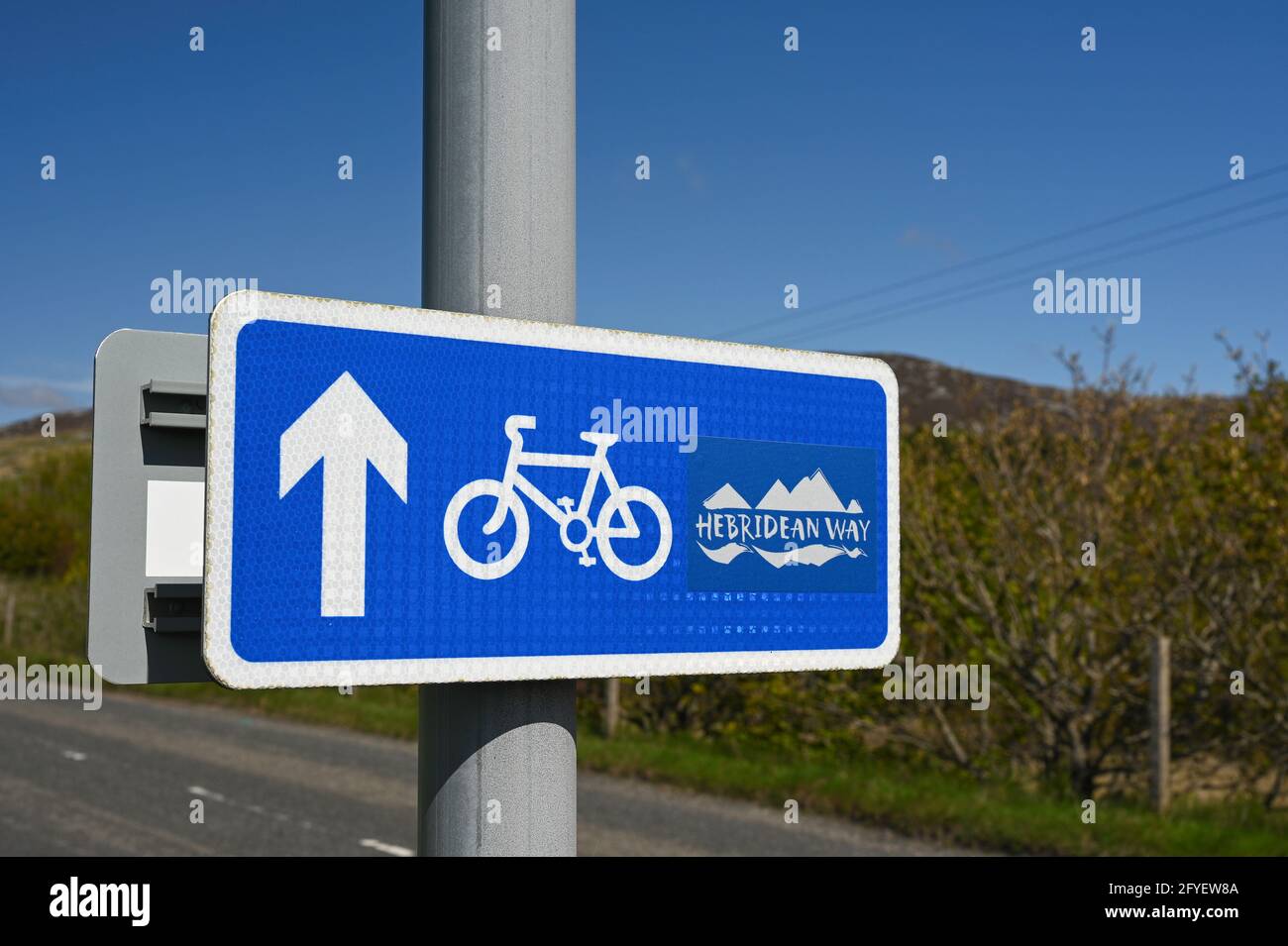 Sign for Hebridean Way cycle route. Text, bicycle icon, arrow. Blurred background of road Stock Photo