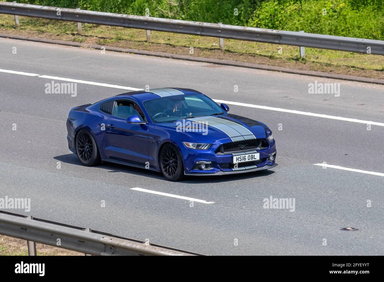 2016 Ford Mustang GT Blue 4951cc muscle car; Vehicular traffic, moving vehicles, cars, vehicle driving on UK roads, motors, motoring on the M61 UK motorway network. Stock Photo