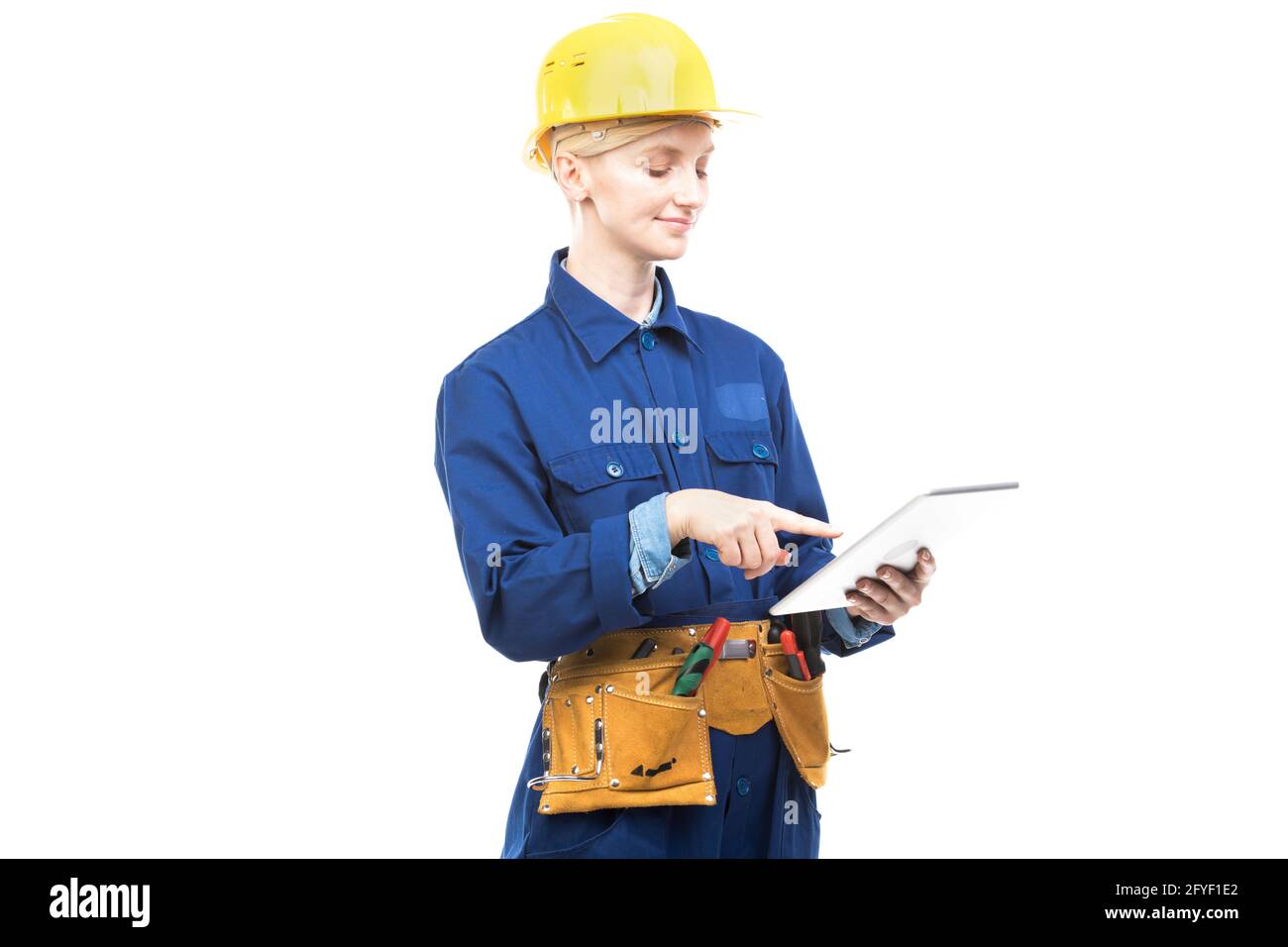 Horizontal medium portrait of modern professional female construction worker wearing blue uniform using digital tablet, white background Stock Photo
