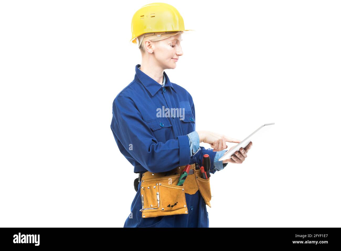 Horizontal medium portrait of modern professional female construction worker wearing blue uniform using digital tablet, white background Stock Photo