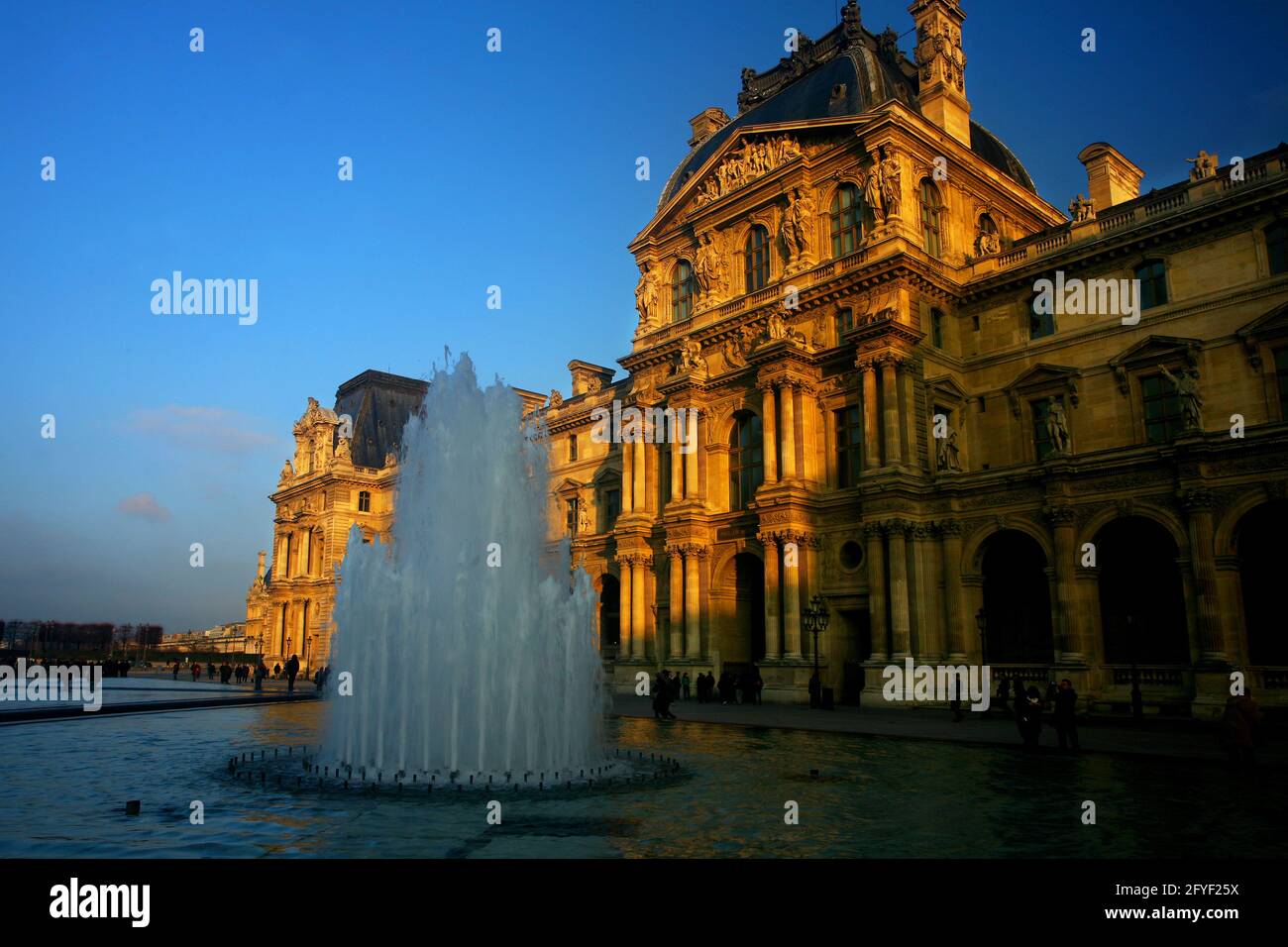 Der Louvre von der Sonne angestrahlt mit Springbrunnen in Paris in Frankreich Stock Photo