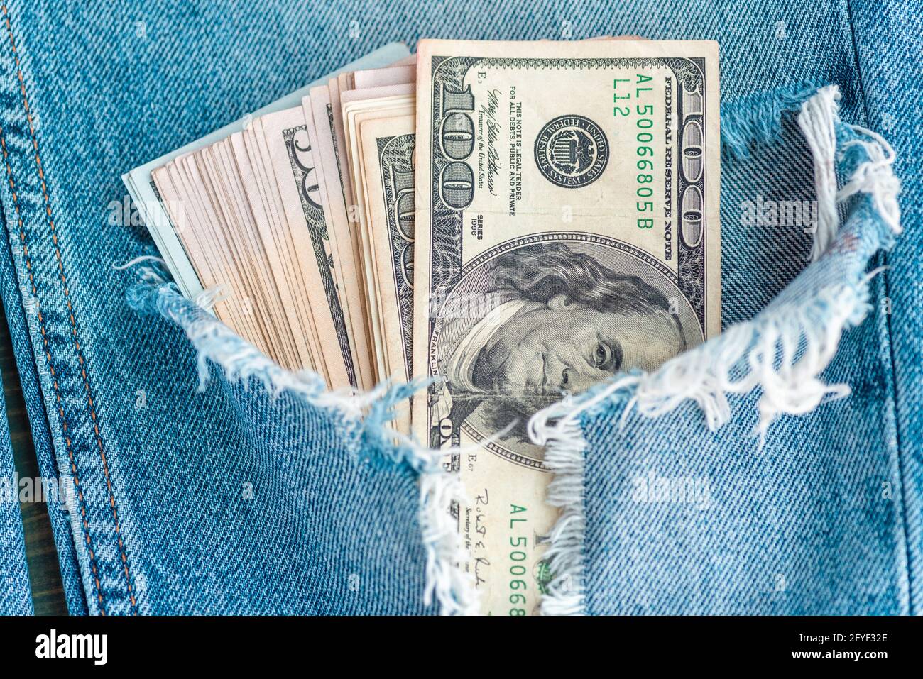 Macro shot of trendy jeans with US dollar bills in a pocket. Dollars in jeans. Financial concept. Stock Photo