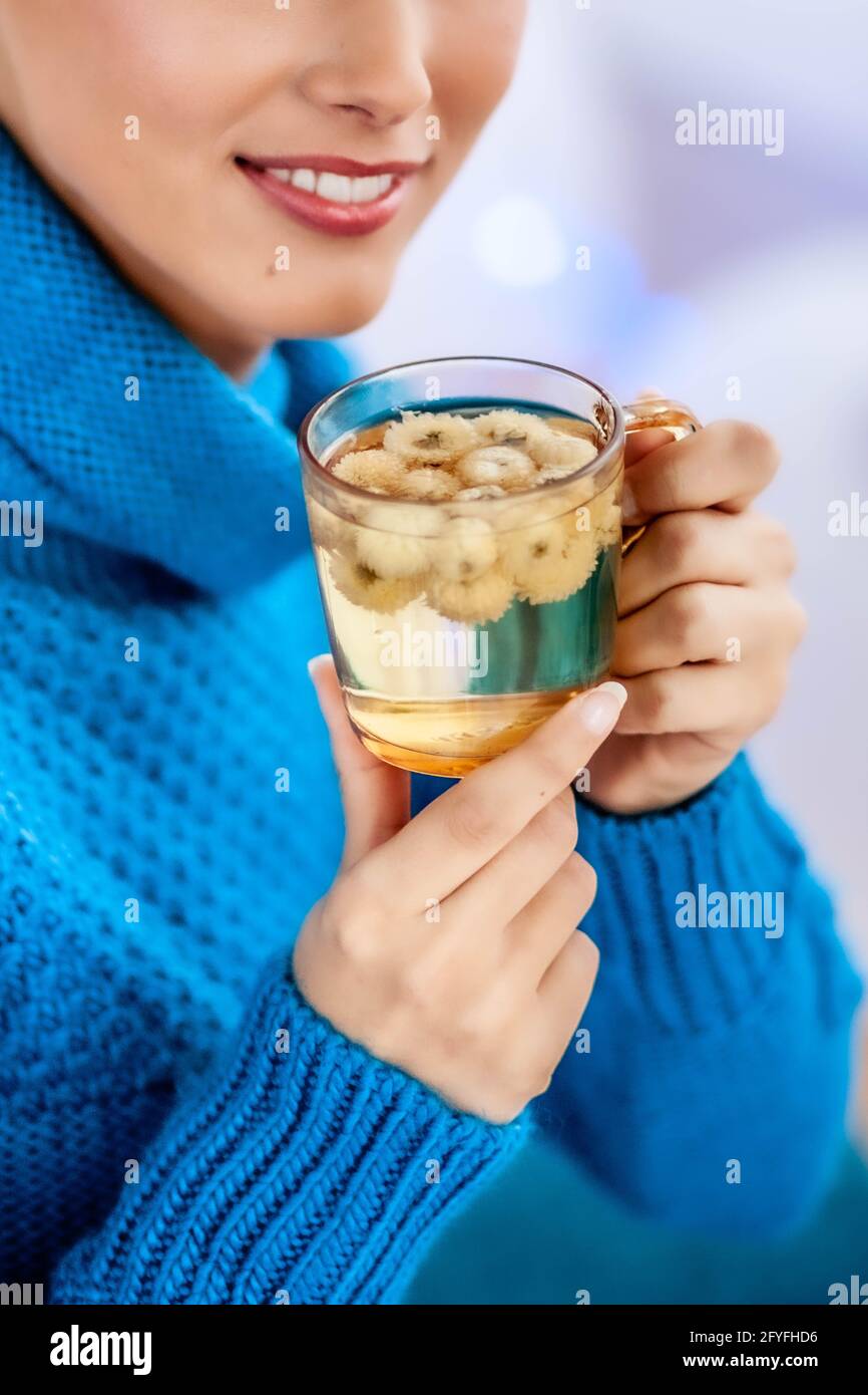 Woman drinking infusion of dry camomile flowers. Stock Photo