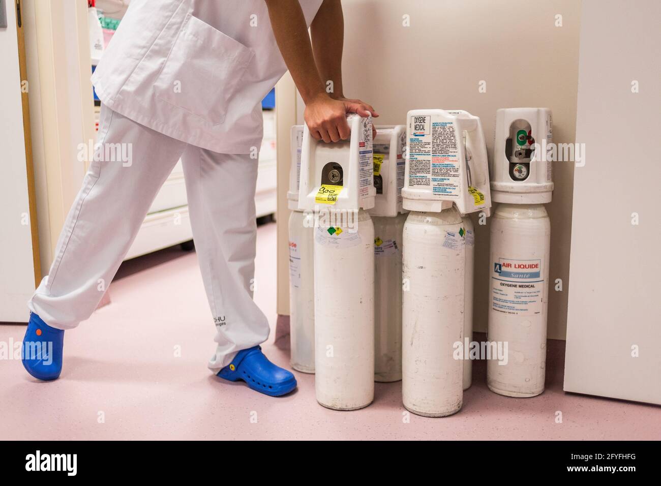 A nurse transports a medical oxygen cylinder to a COVID hospitalization unit, CHU Limoges, France. Stock Photo