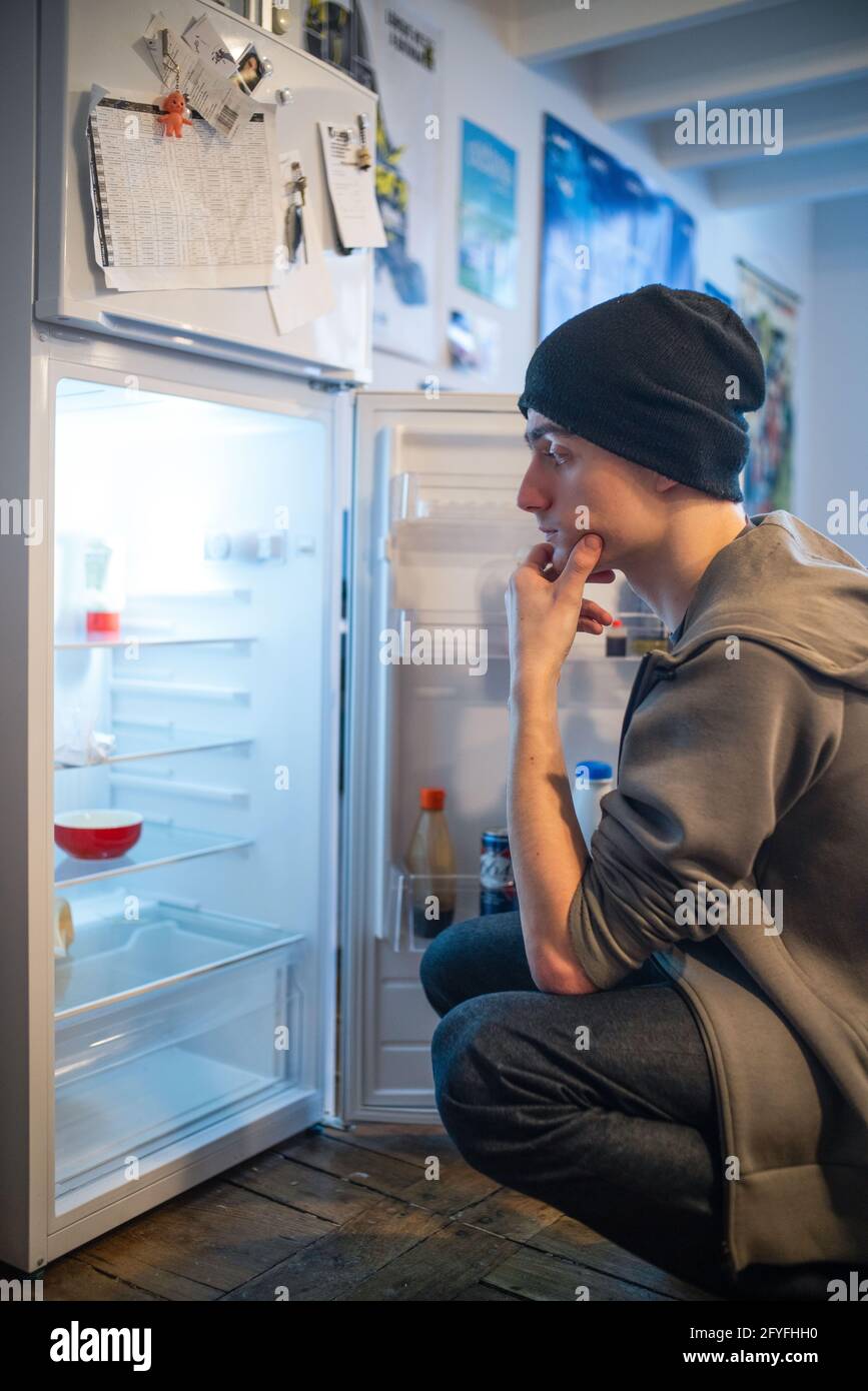 Young man in front of his refrigerator. Illustration on the precariousness of young people, France. Stock Photo