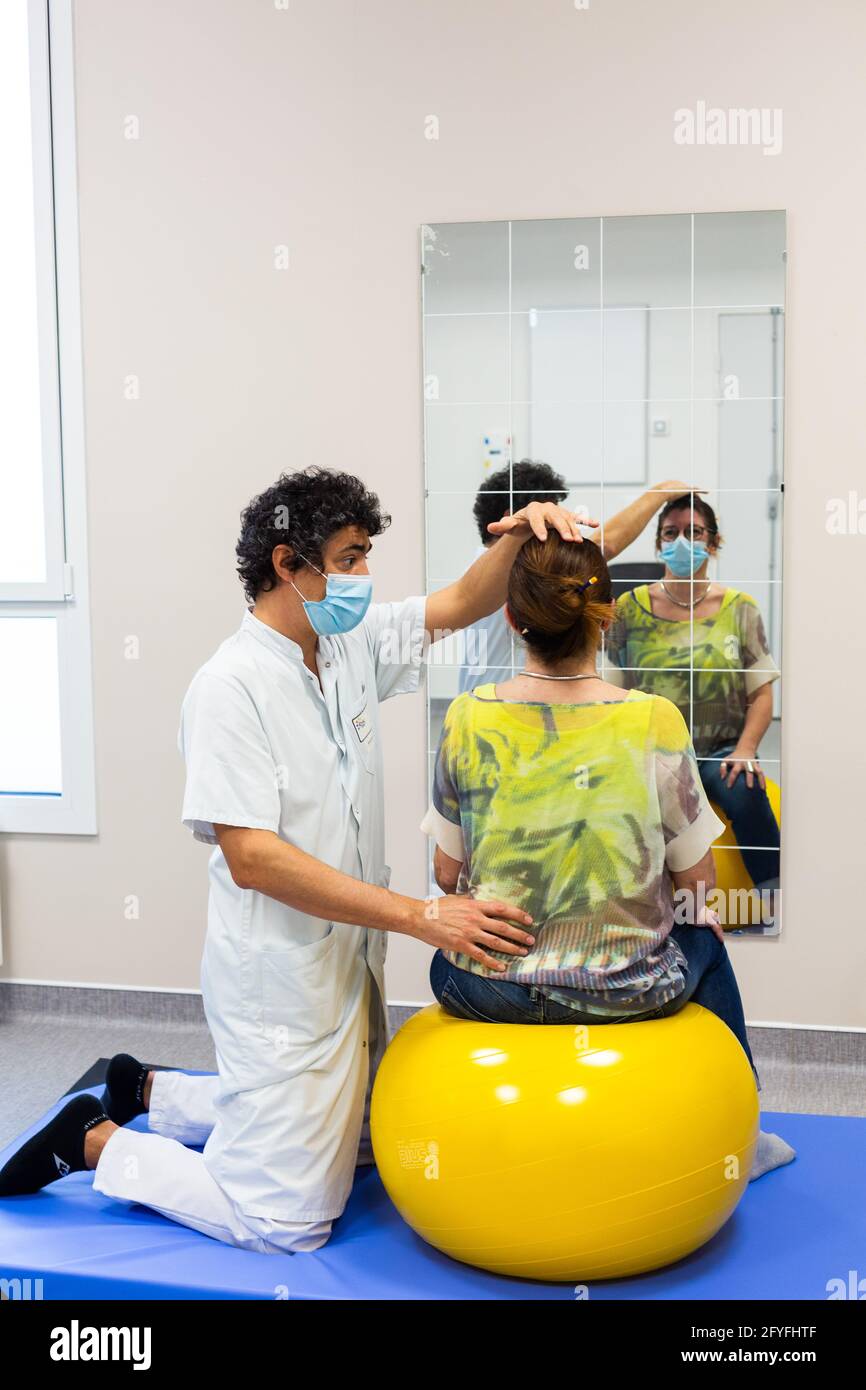 Muscle strengthening session with a physiotherapist to relieve lower back pain with a rehabilitation ball (Swiss Ball). Limoges hospital, France. Stock Photo