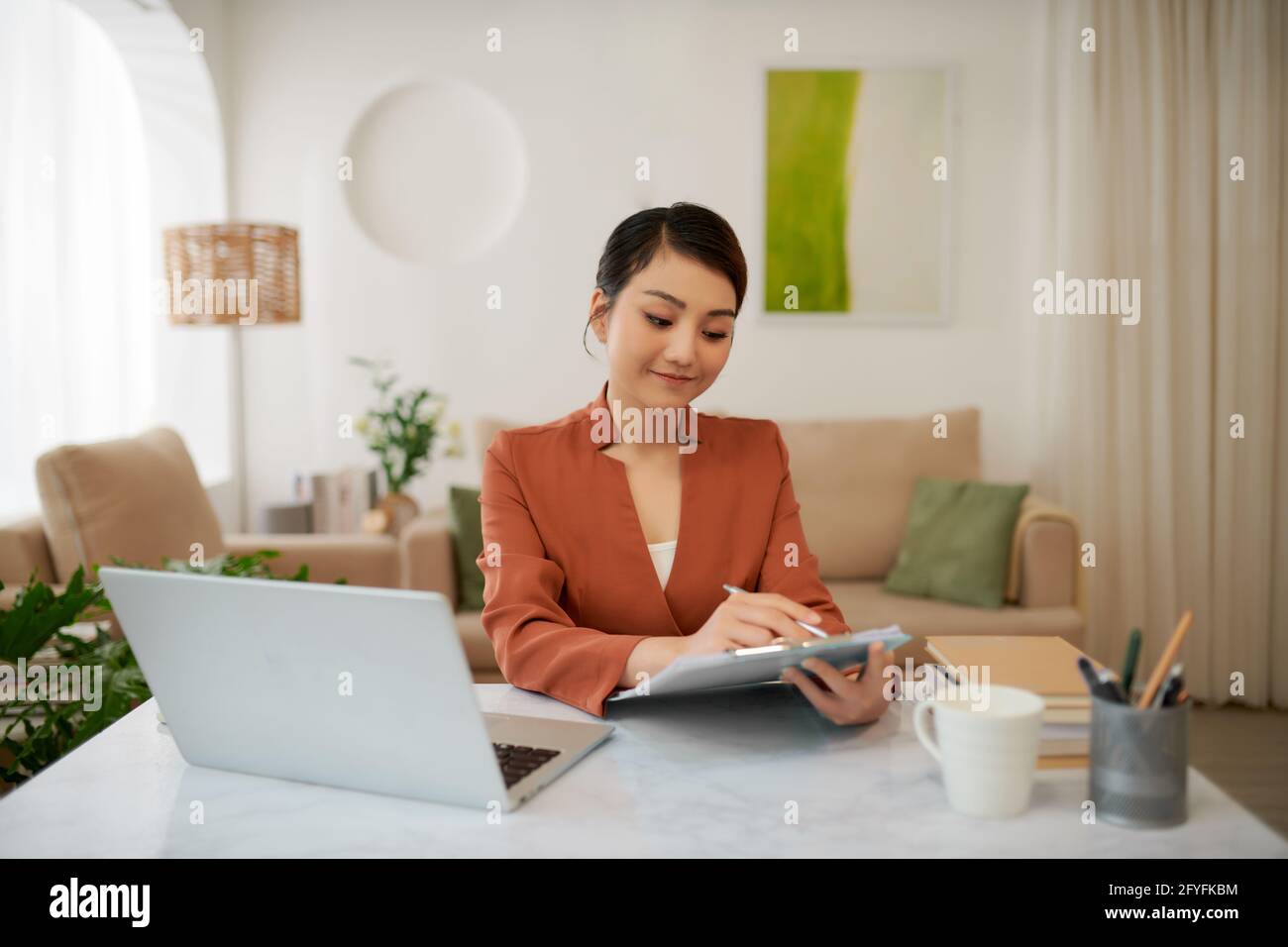 Mature successful business woman looking at mobile cell phone while at home in office work space Stock Photo