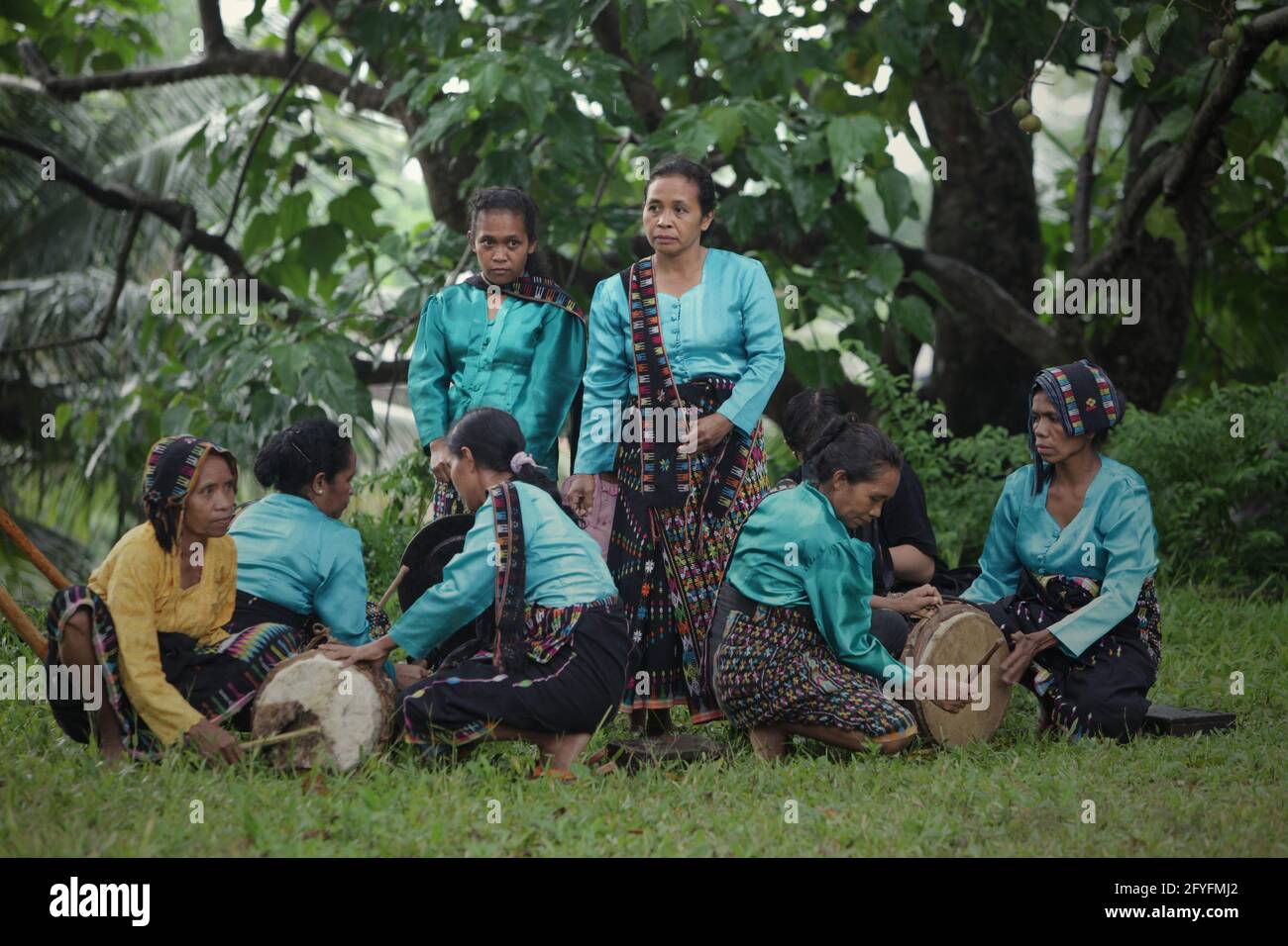 Women playing percussive instruments as musical background for a show of "caci" (Flores Island's traditional whip fight, martial art) in Liang Ndara village, Mbeliling, West Manggarai, Flores, East Nusa Tenggara, Indonesia. Stock Photo