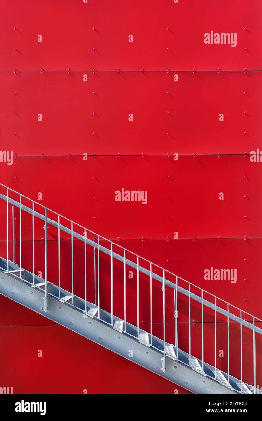 Metal staircase outdoors in front of a red wall Stock Photo