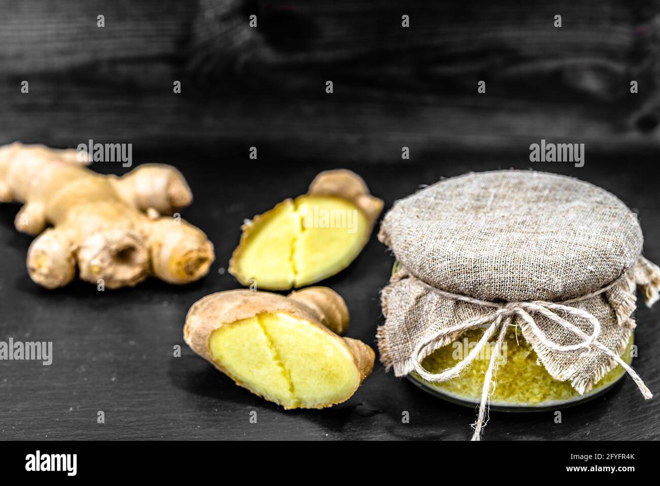 Grated ginger in jar on black background, spices in cuisine for cooking