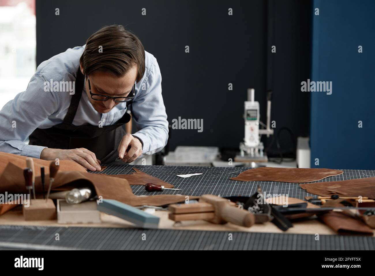 Skilled leather manufacture worker cutting some samples. Stock Photo
