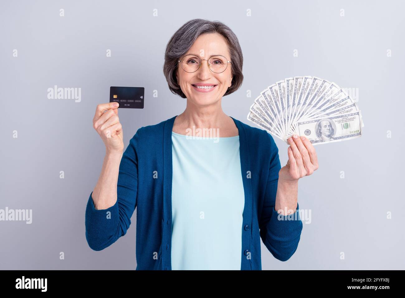 Photo of cheerful lovely old woman hold hands money cash credit card ...