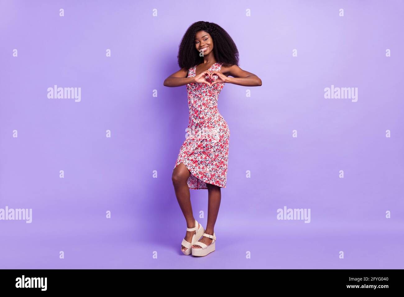 Full length body size photo of smiling woman wearing floral dress showing heart sign isolated pastel purple color background Stock Photo Alamy