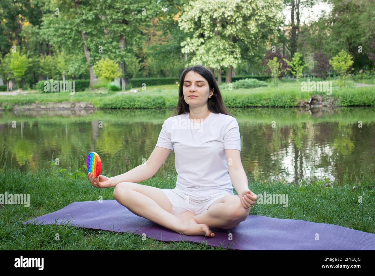 A woman meditates in nature and eats a reusable bubble wrap pop it  antistress toy. Deal with stress at work with Pop it, yoga and meditation  Stock Photo - Alamy