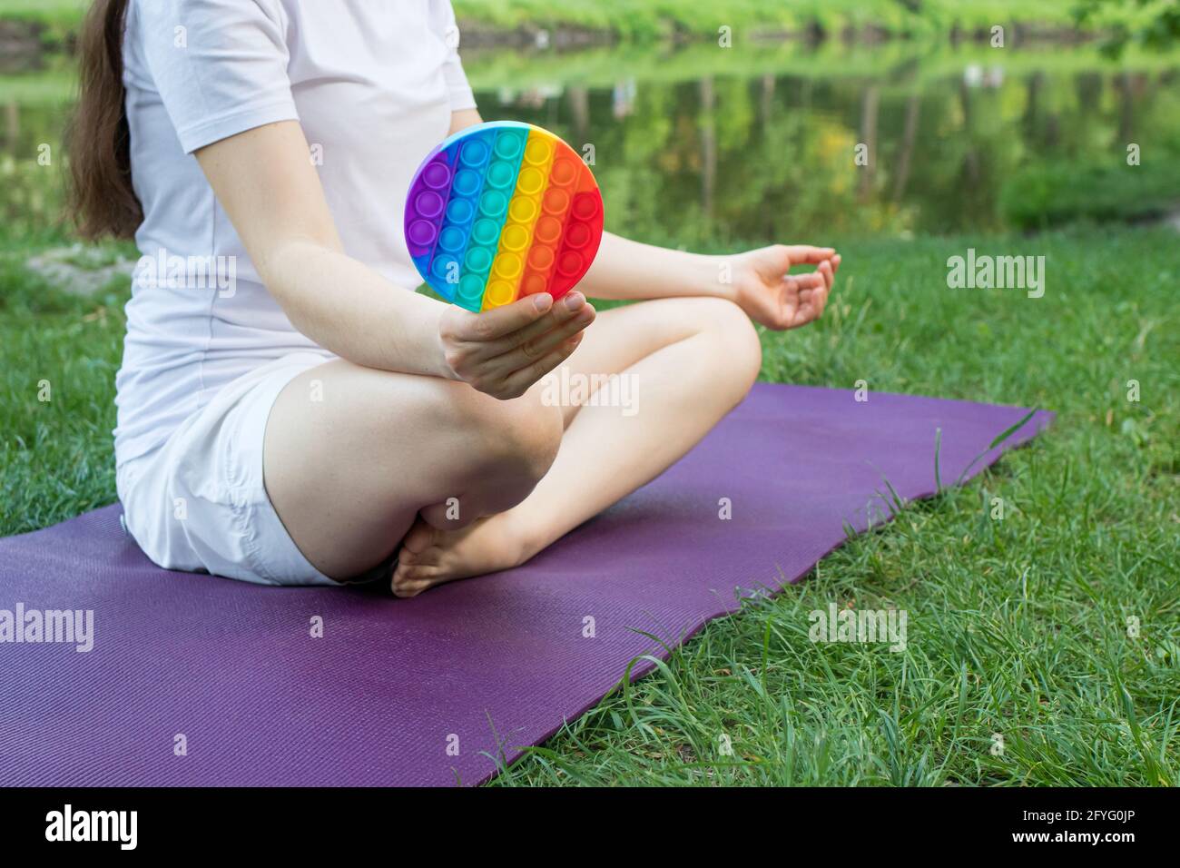 A woman meditates in nature and eats a reusable bubble wrap pop it antistress toy. Deal with stress at work with Pop it, yoga and meditation Stock Photo - Alamy