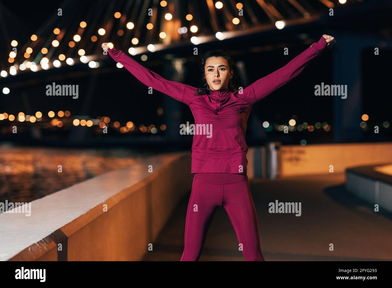 Young middle eastern woman in sports clothes doing warming up exercises outdoors Stock Photo