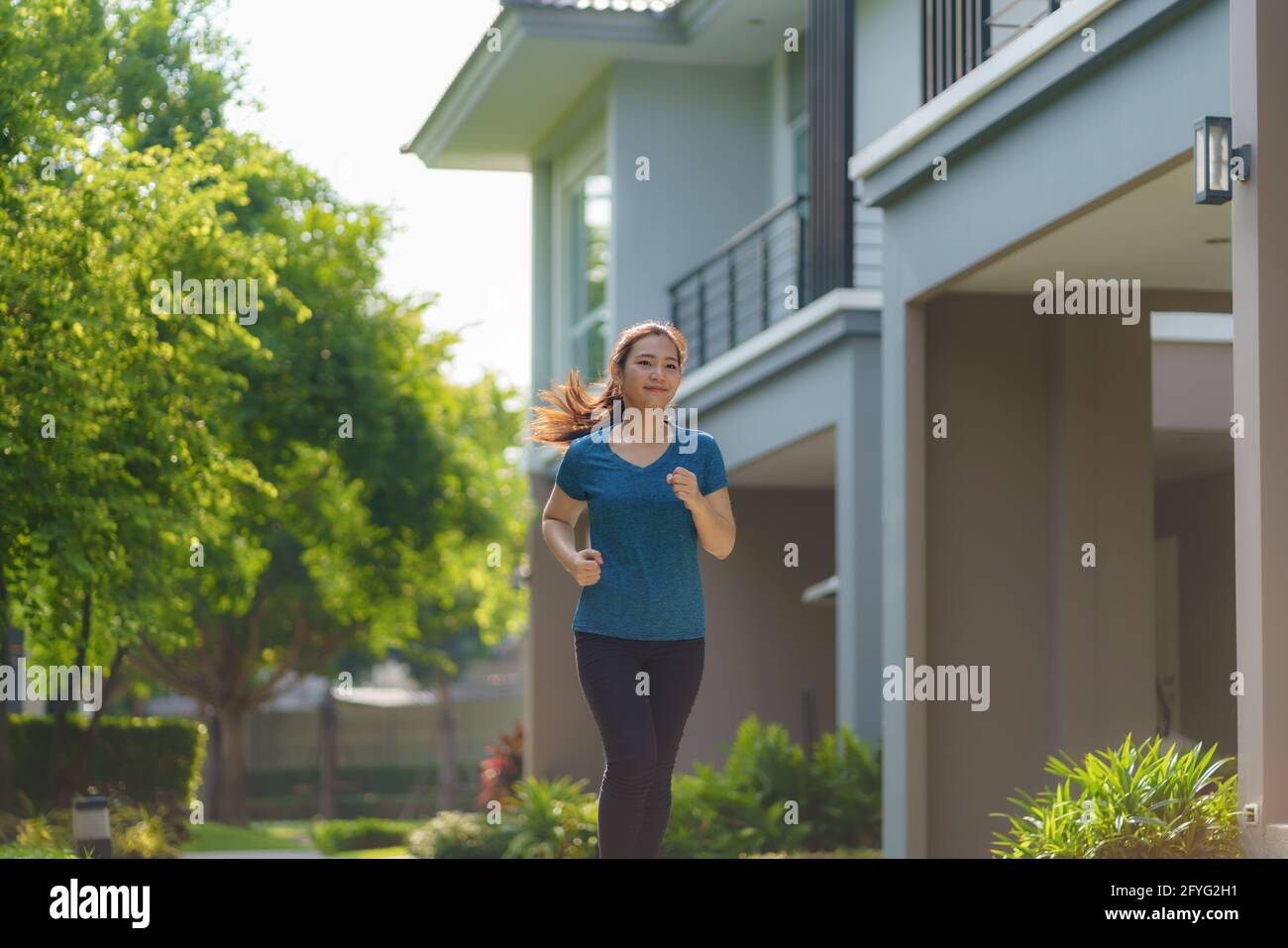 Asian woman are jogging in the neighborhood for daily health and well being, both physical and mental and simple antidote to daily stresses and to soc Stock Photo