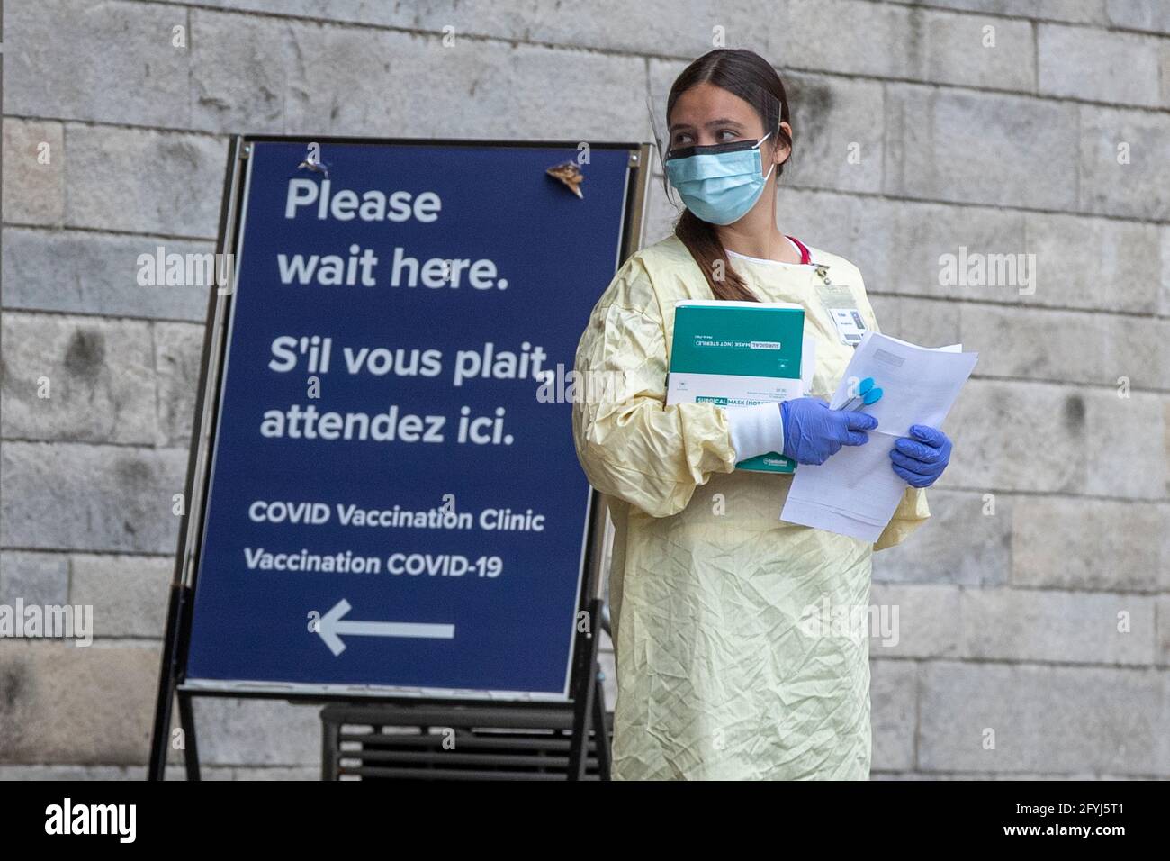 A person in PPE (Personal protective equipment) waits outside a COVID-19 vaccine clinic at Kingston general hospital (KGH) in Kingston, Ontario on Thu Stock Photo