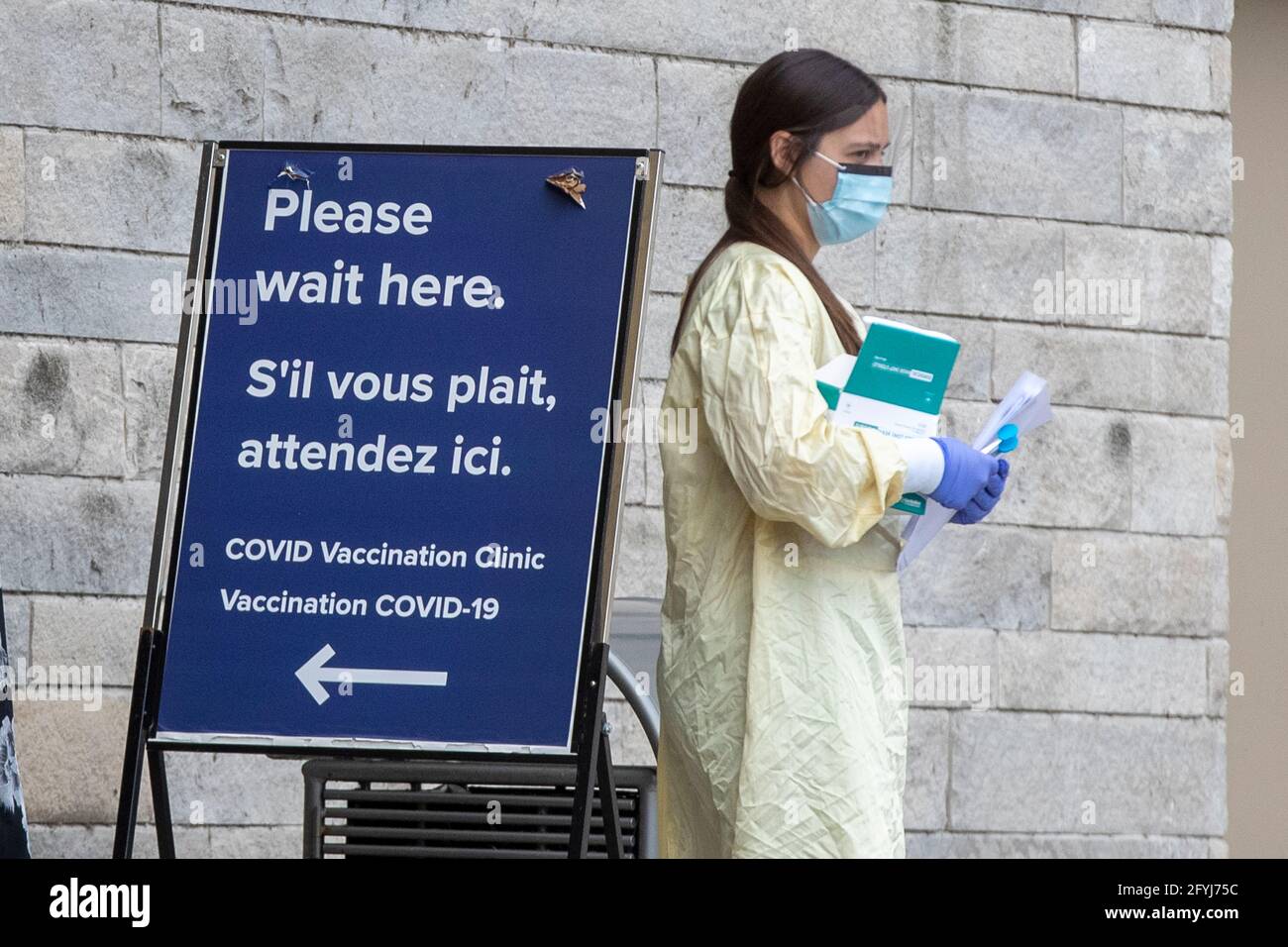 A person in PPE (Personal protective equipment) waits outside a COVID-19 vaccine clinic at Kingston general hospital (KGH) in Kingston, Ontario on Thu Stock Photo
