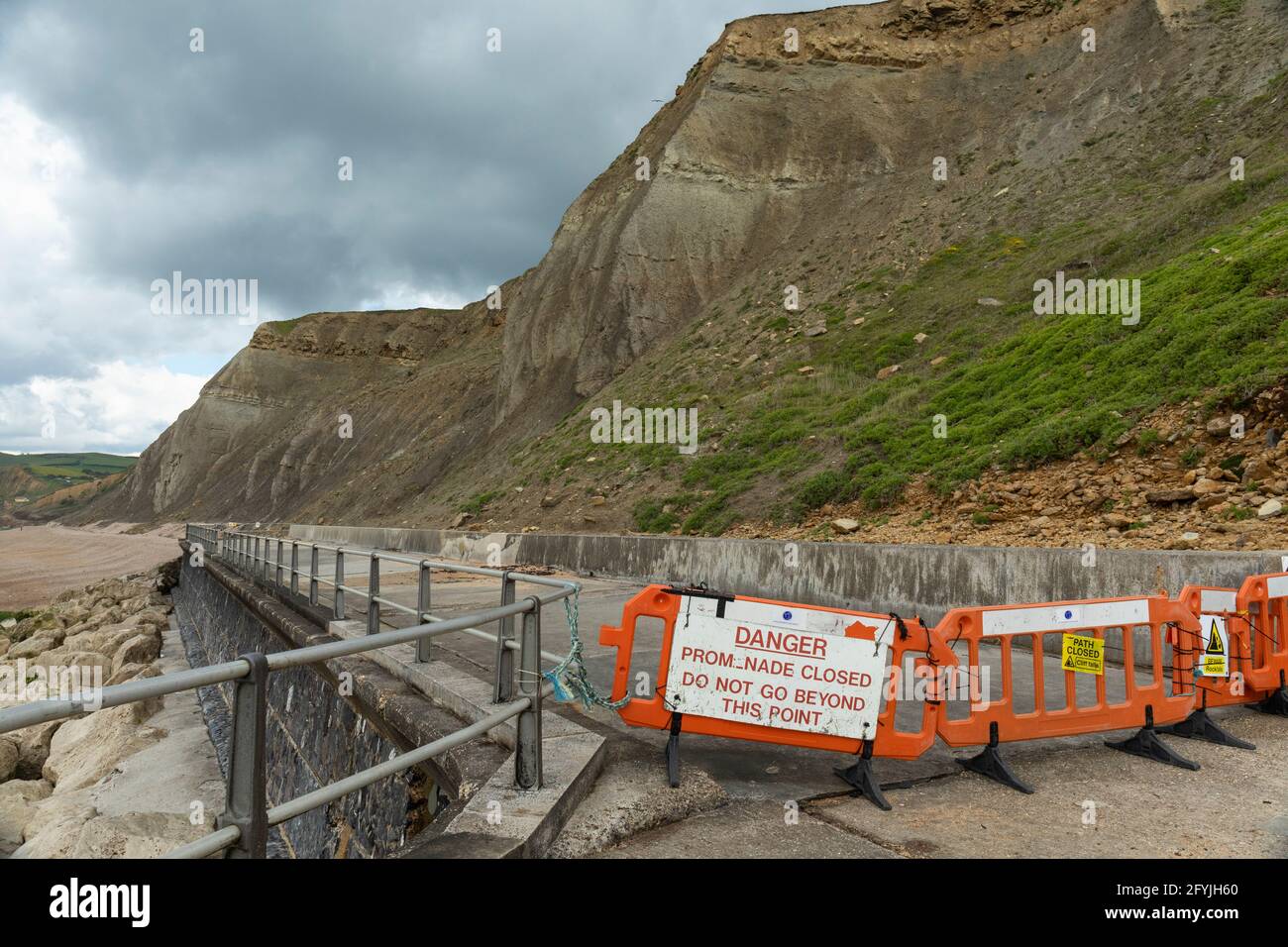 Warning sign alerting that the promenade coastal path is closed due to Danger to the public of rock falls. West Bay, Dorset, England, UK Stock Photo