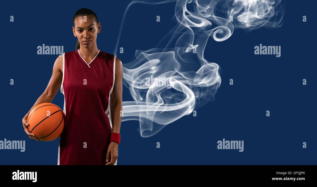 Composition of mixed race female basketball player holding ball with smoke and copy space Stock Photo