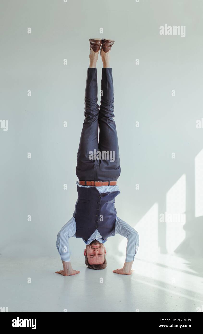 Portrait of a smiling man in a shirt and waistcoat doing a headstand Stock Photo