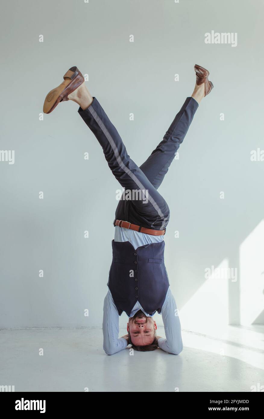 Portrait of a smiling man in a shirt and waistcoat doing a headstand Stock Photo