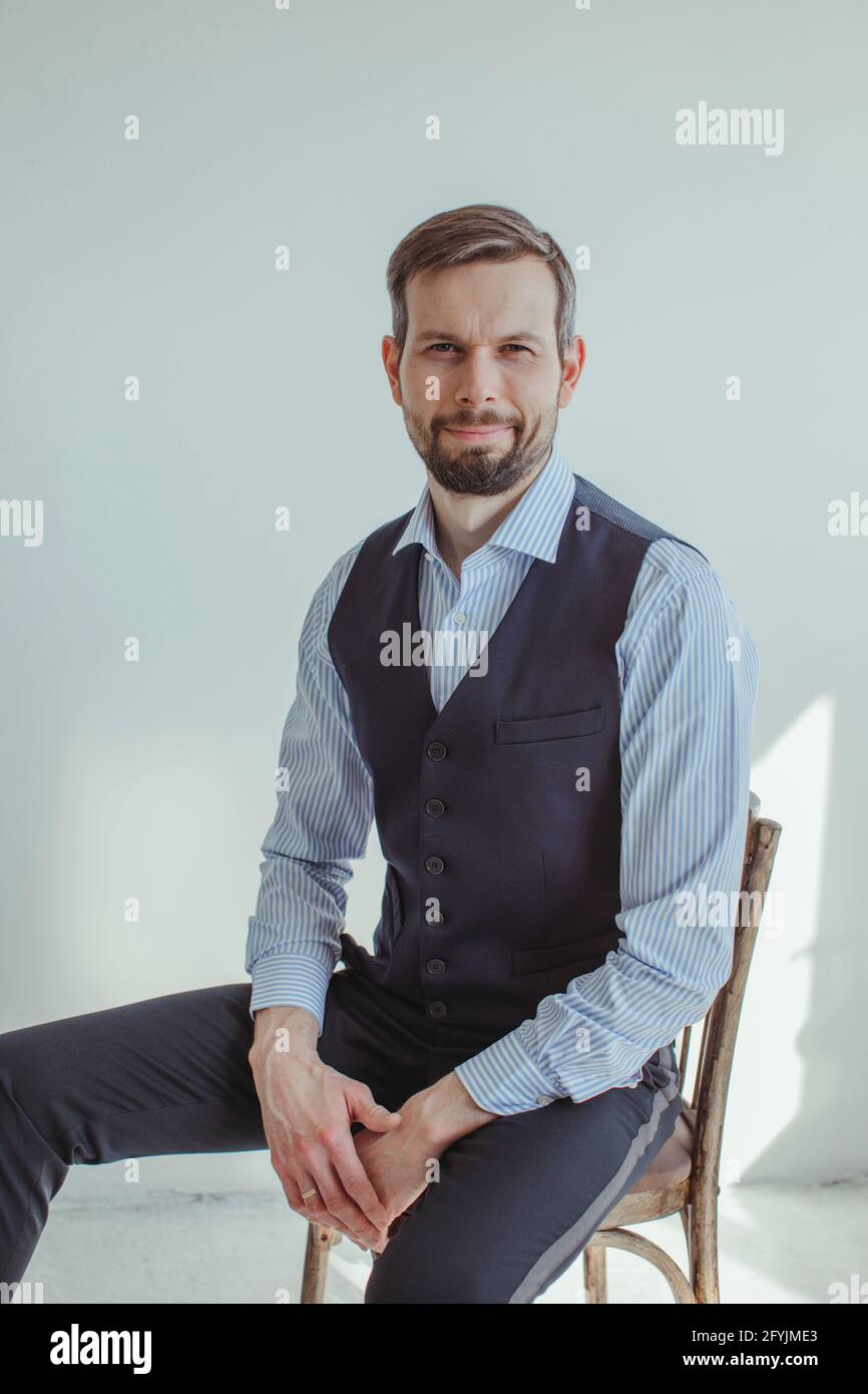 Portrait of a smiling man in a shirt and waistcoat sitting on a chair Stock Photo