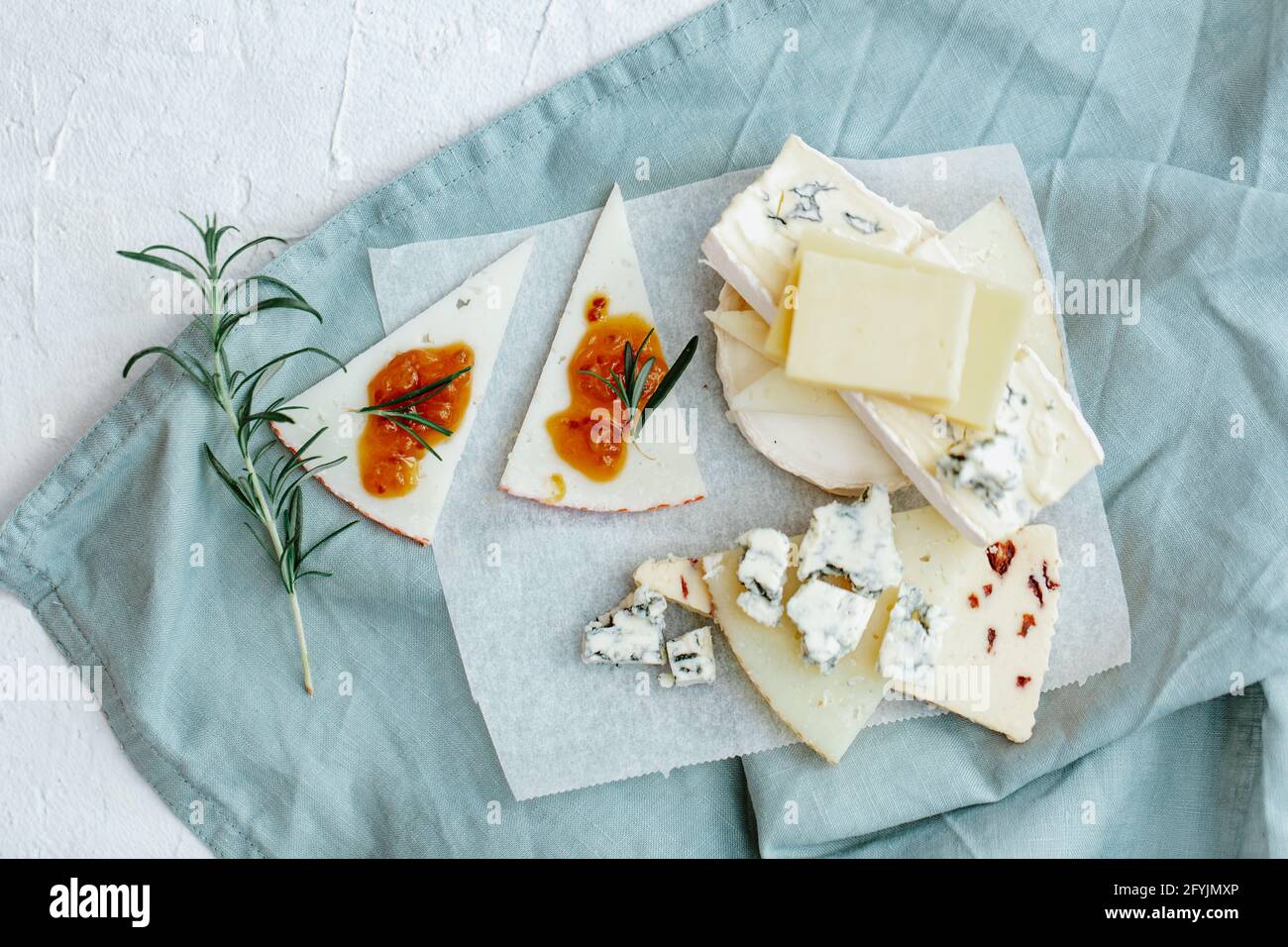 Overhead view of a cheese board with a stack of blue cheese, cheddar, goats cheese and chutney Stock Photo