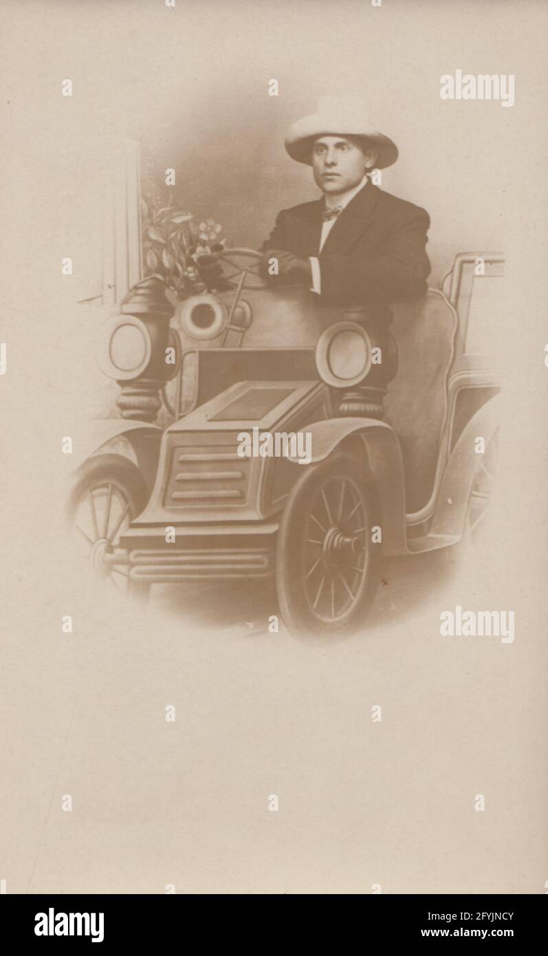 Vintage early 20th century photographic portrait postcard showing a young man pretending to be driving a motor car in Blackpool. Stock Photo