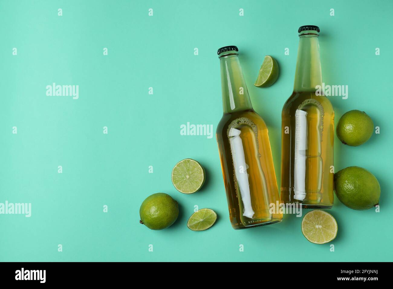 Bottles of beer and limes on mint background Stock Photo