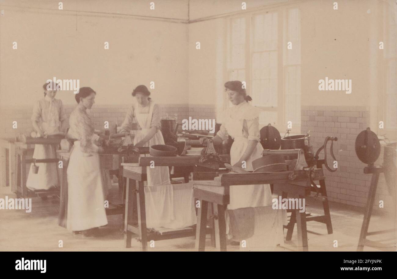 Vintage early 20th century photographic postcard showing a group of young ladies washing and pressing the linen. Stock Photo
