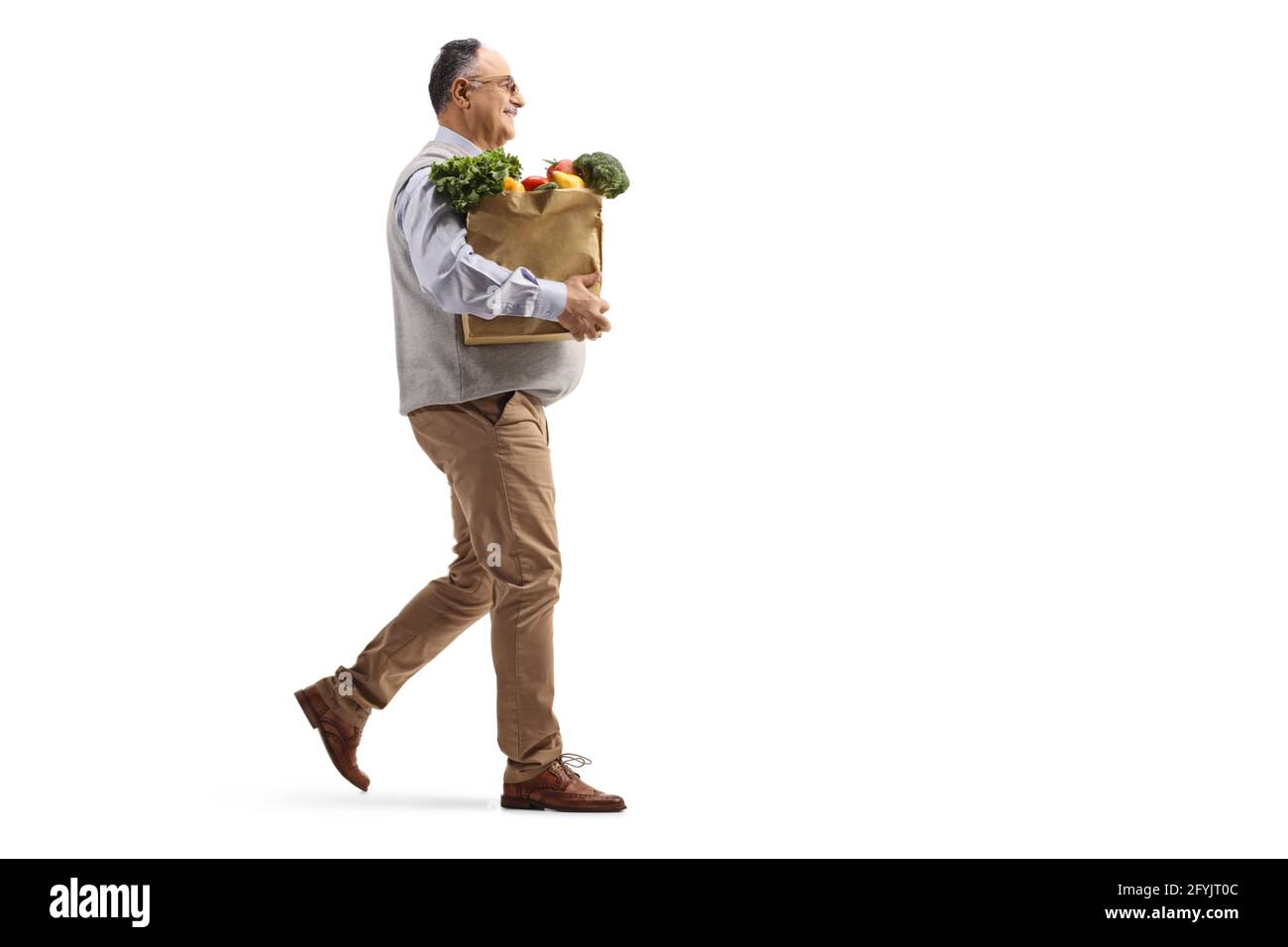 Full length profile shot of a mature man walking with a grocery bag isolated on white background Stock Photo