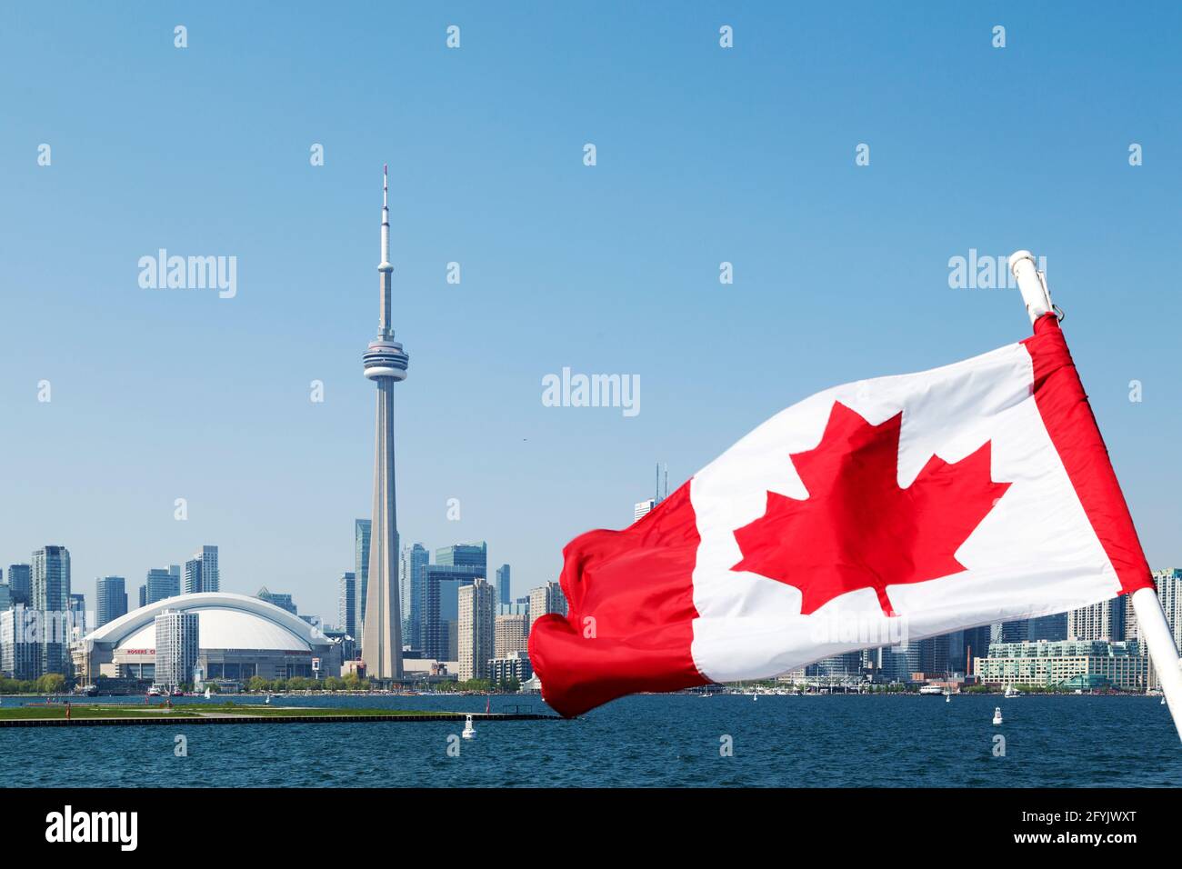 The Canadian national flag and the cityscape of Toronto in Ontario, Canada. The domed roof of the Rogers Centre baseball stadium and CN Tower are seen Stock Photo