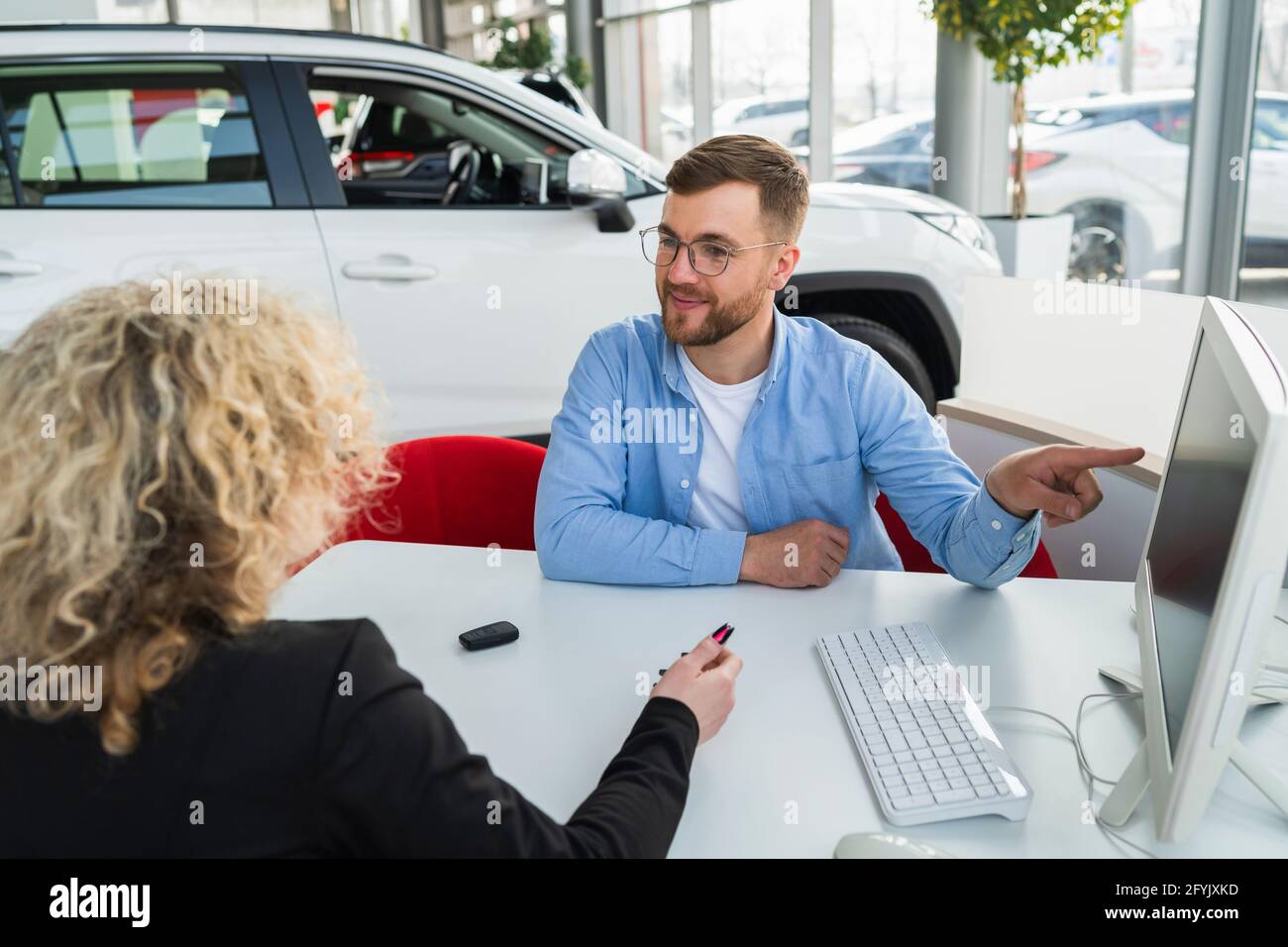 Car dealership manager with client at computer in showroom Stock Photo