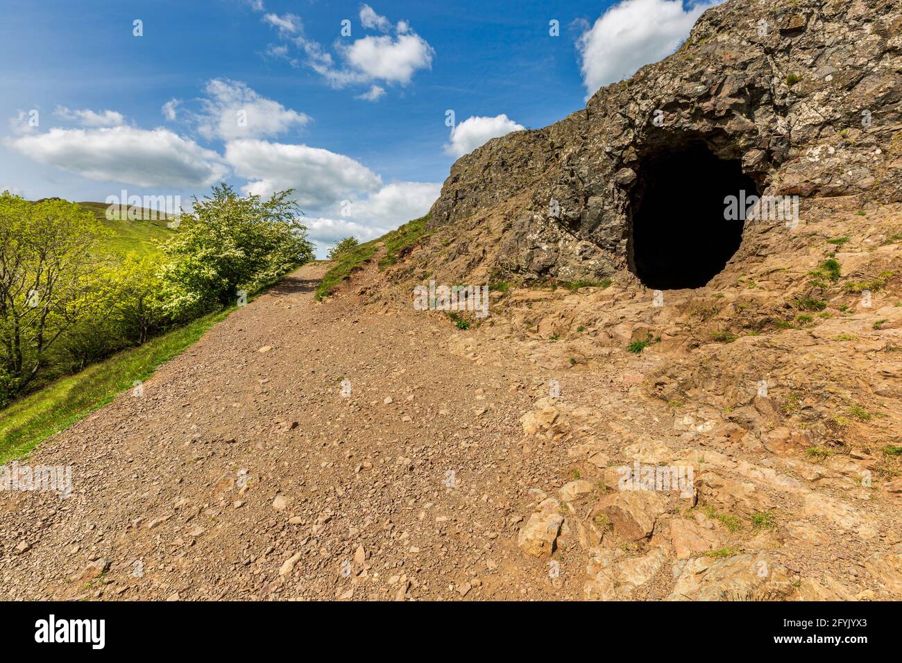 The entrance to Clutter’s Cave in the Malvern Hills with British Camp in the background, Worcestershire, England Stock Photo