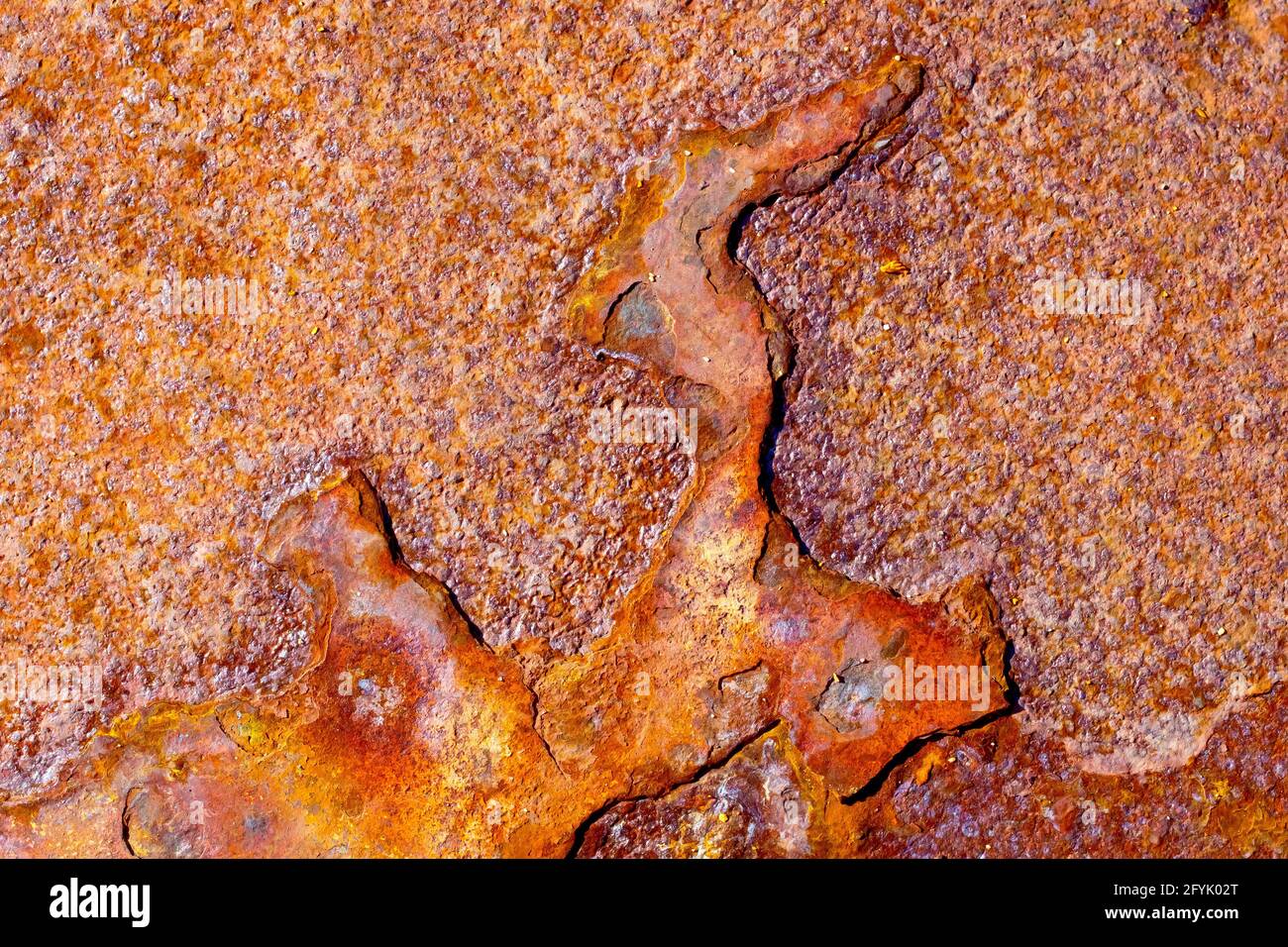 Close up of the pattern of corrosion on the surface of a rusty sheet of metal showing various degrees of oxidation. Stock Photo